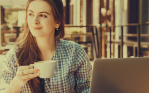 woman on vacation, working on laptop drinking coffee